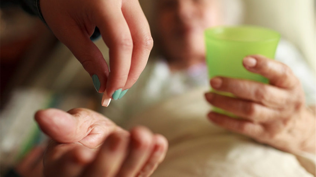 Cupped hand of elderly woman receiving pill