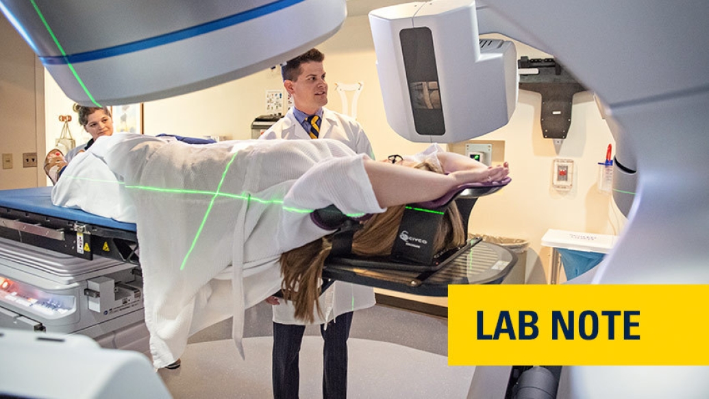 doctor in white coat scanning person in machine with words &quot;lab note&quot; written on yellow badge with blue font bottom right