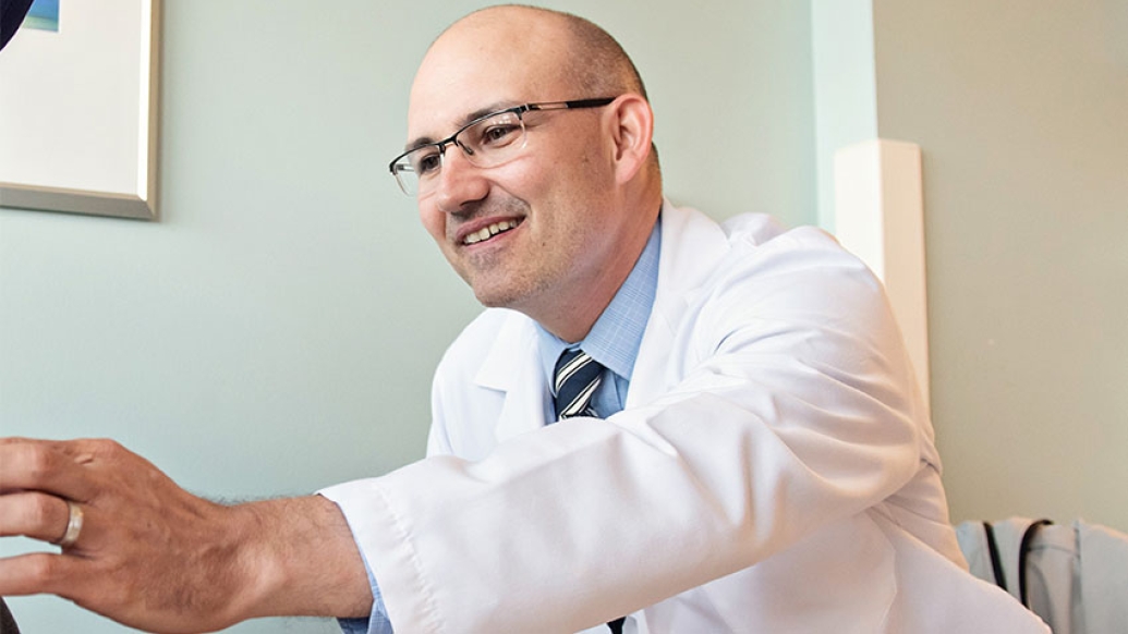 Doctor in room reaching out smiling
