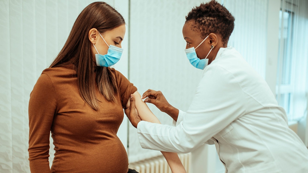pregnant woman getting vaccine with doctor with masks on