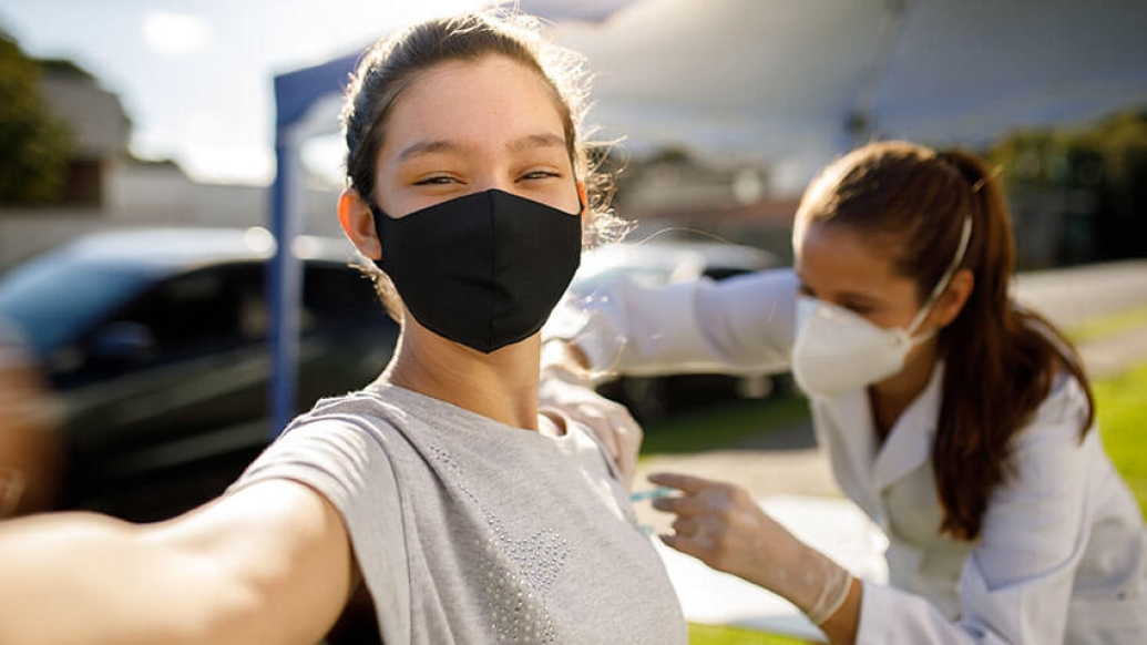 Teen taking a selfie with vaccination doctor mask on.