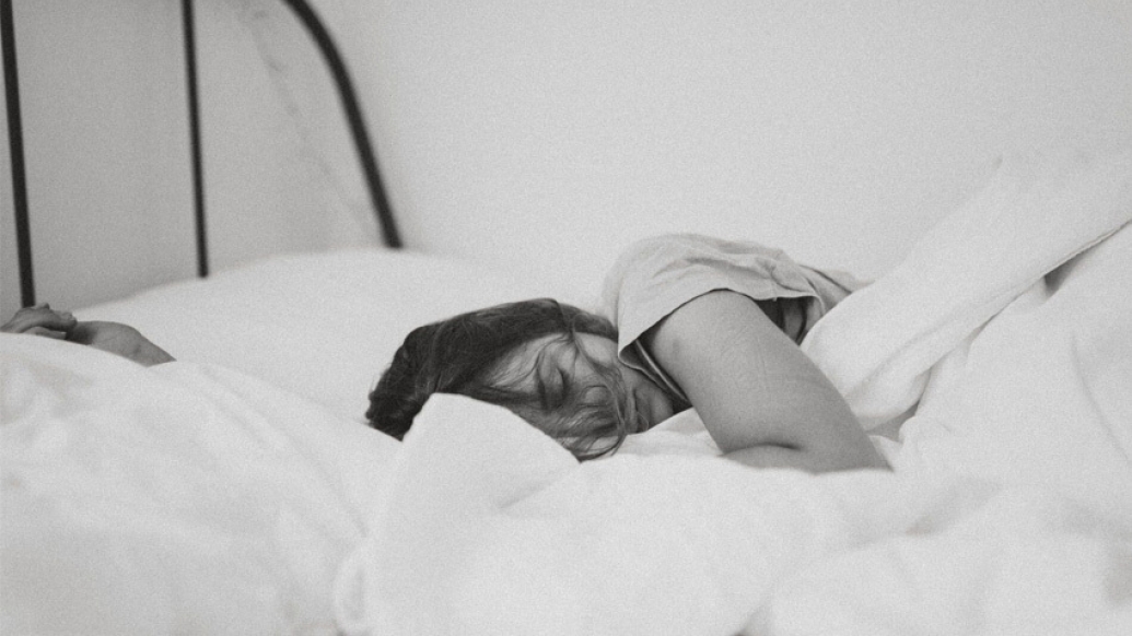 woman sleeping in bed with blanket in black and white photo