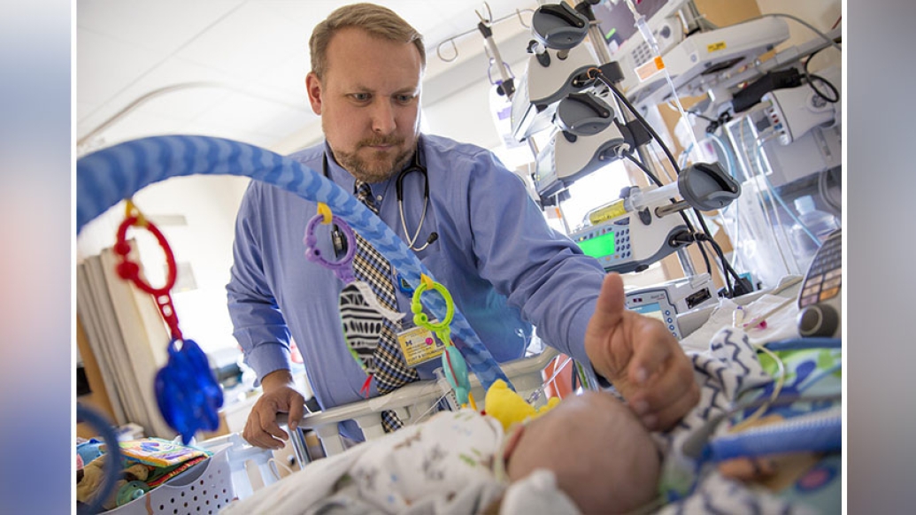 Provider standing over baby with pacifier in hospital