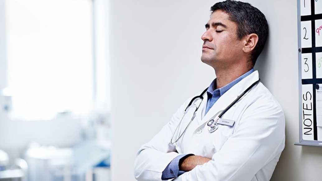 internist closing eyes and leaning against wall